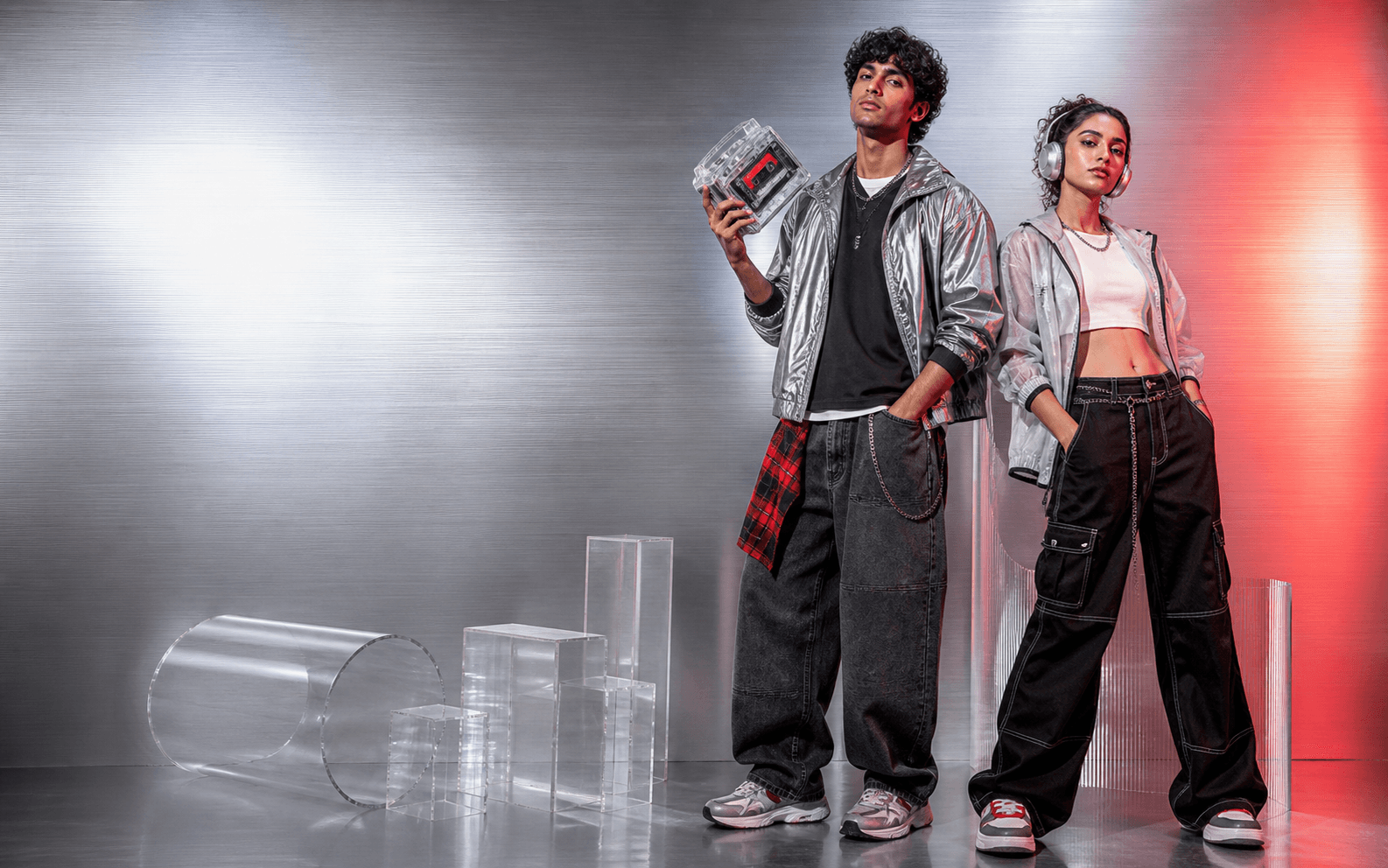 Two young Indian adults wearing contemporary streetwear in a silver studio